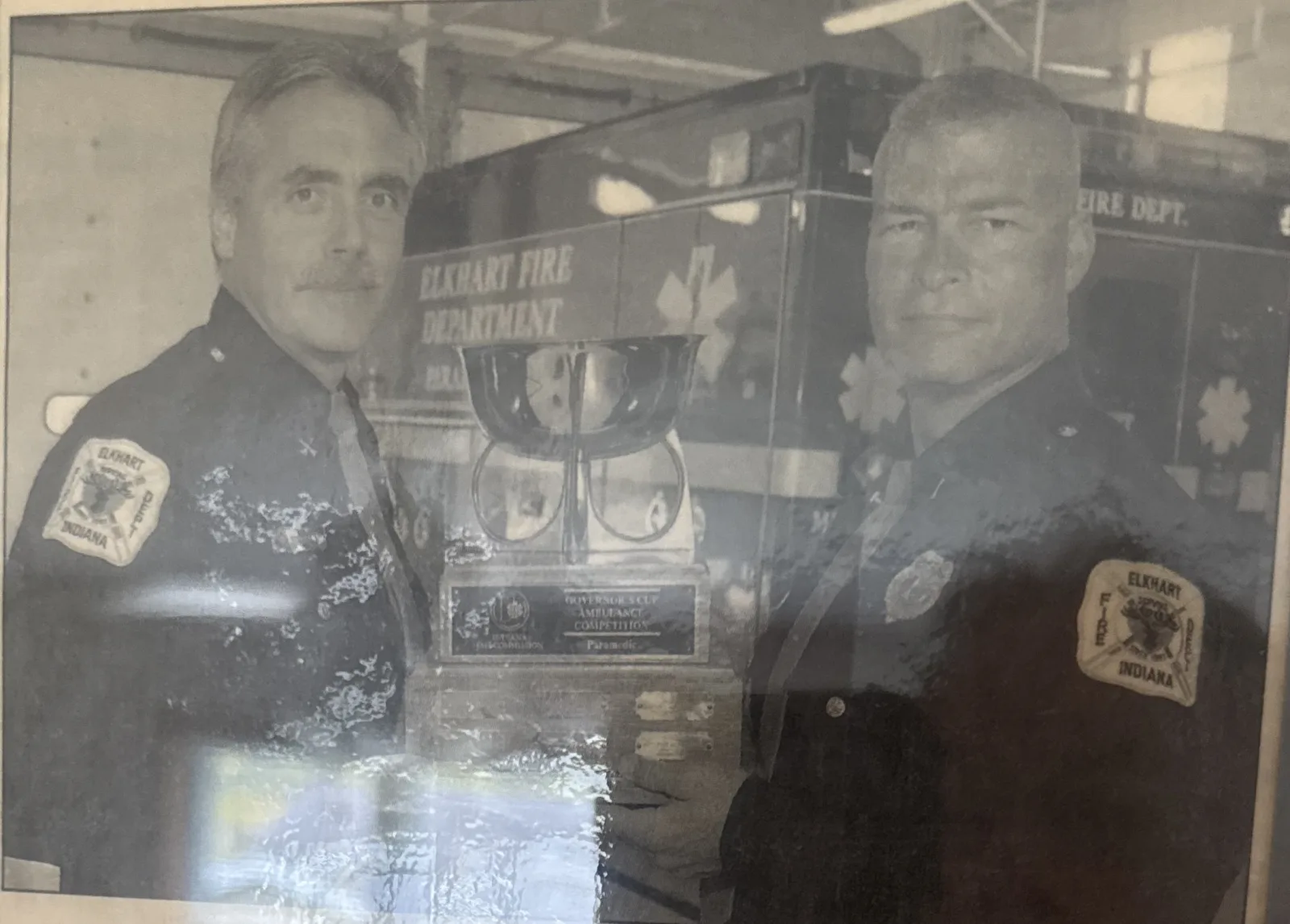 Capt. Vito Palumbo and Lt. Grant Roberts in dress uniform beside an ambulance with the Governor's Cup trophy